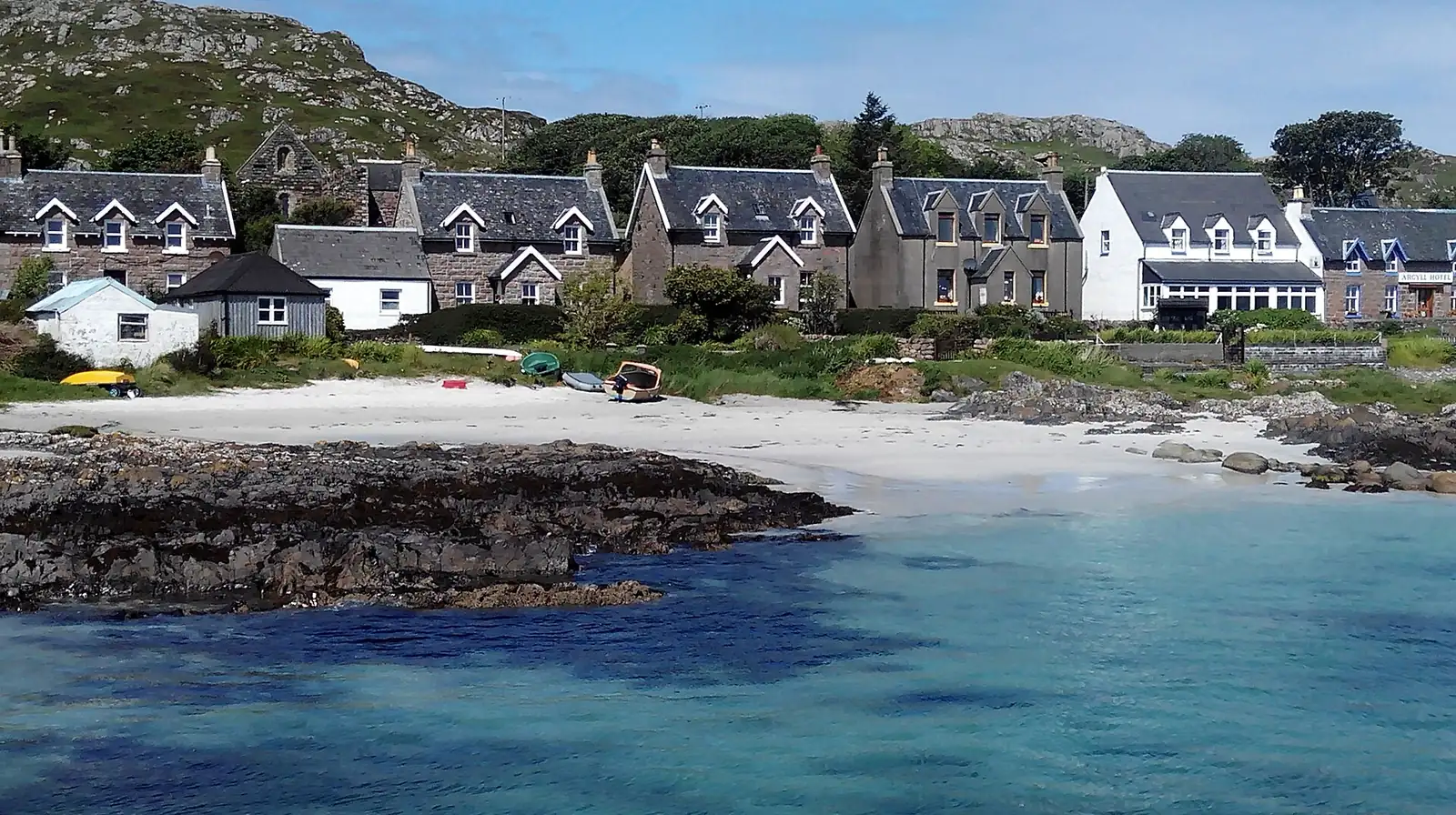 Il villaggio di Baile Mòr sull'isola di Iona, con la spiaggia di sabbia chiara e l'acqua verde-salvia in primo piano